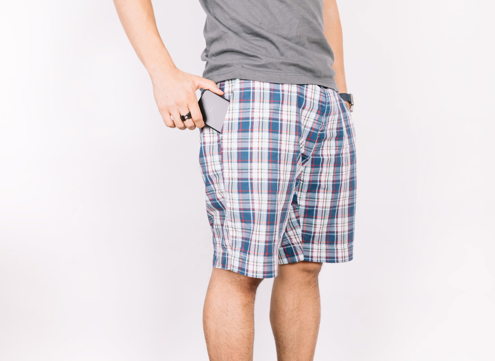 チェック柄ショートパンツのポケットにスマホを入れる男性