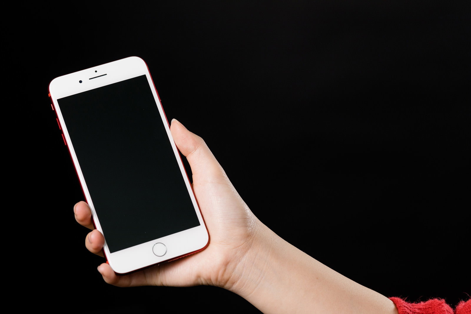 赤いフレームのiPhoneを縦向きに持つ女性の手