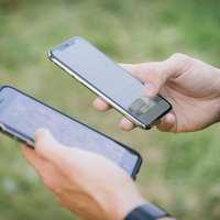 2台のスマホ（iPhone）を操作する男性の手の写真