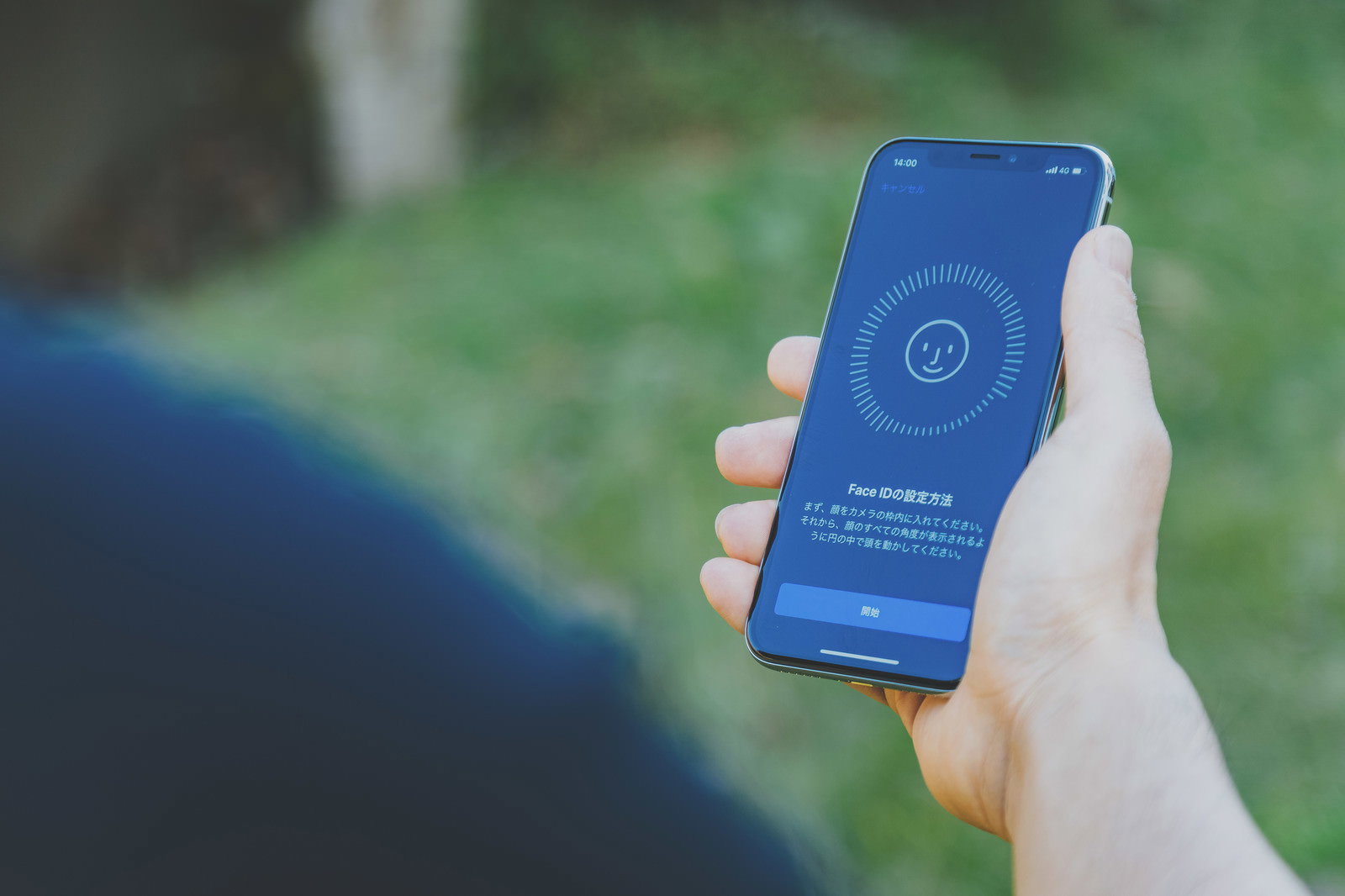 Face IDの設定画面を表示するiPhoneXを手に持っている様子