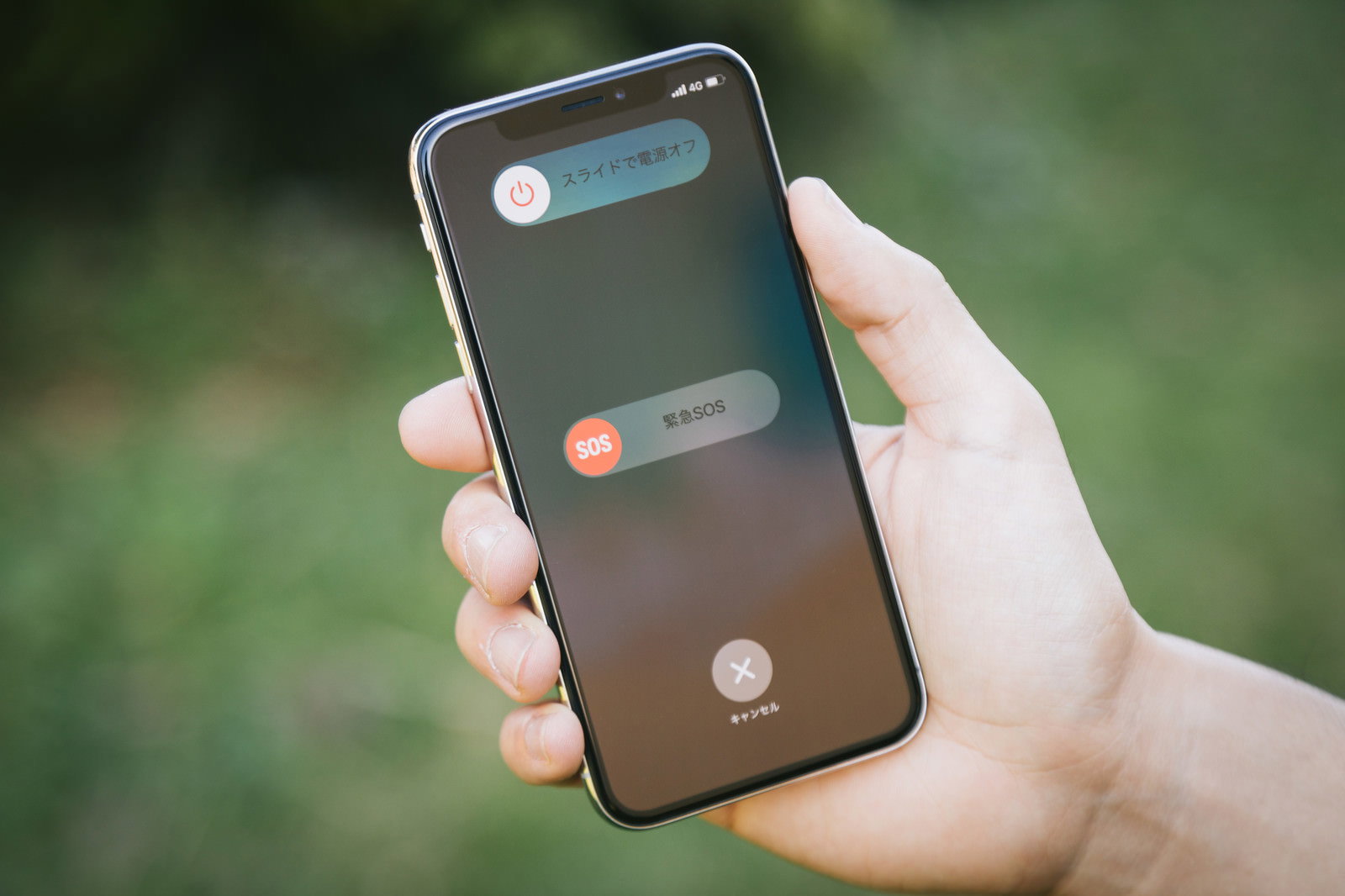 iPhone Xの緊急SOS画面を手に持って表示している様子
