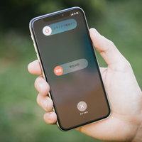 iPhone Xの緊急SOS画面を手に持って表示の写真