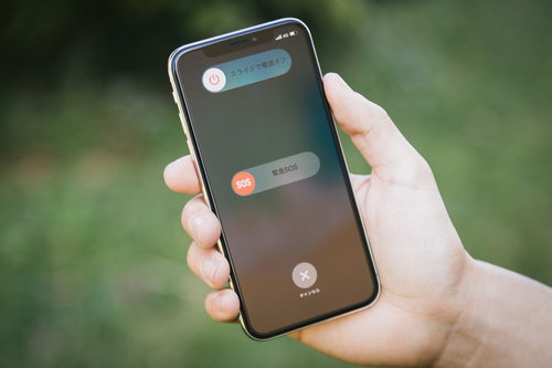iPhone Xの緊急SOS画面を手に持って表示