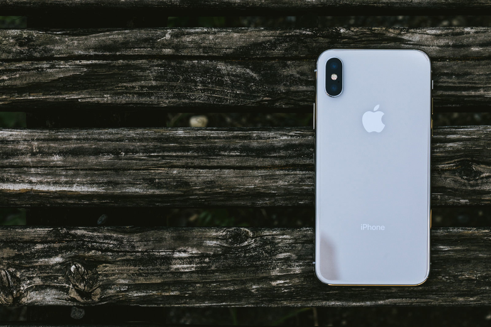 古い木材の質感ある表面に白いiPhone Xが置かれている様子