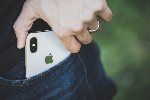 ポケットから iPhone X を取り出す男性の手