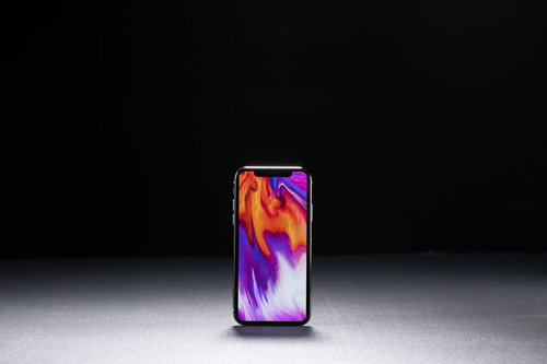 iPhone Xの画面に映るピンク×パープルグラデーション待受