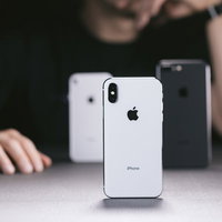 iPhone X と iPhone 8 を並べて考える男性の写真