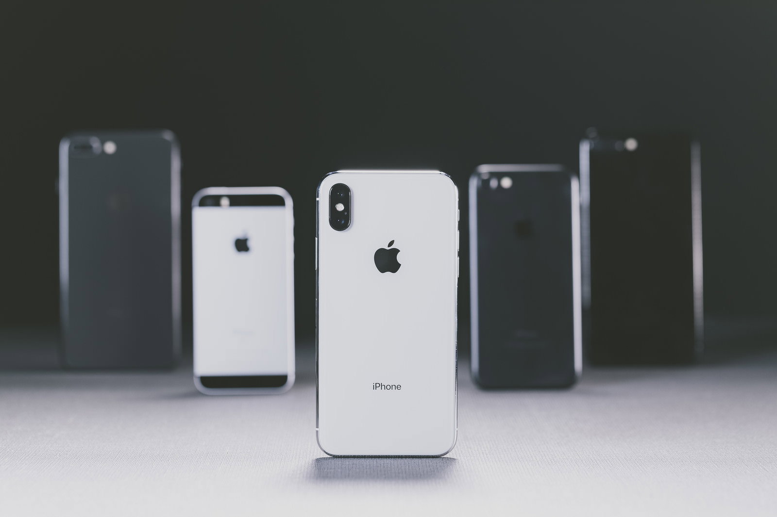 シルバーのiPhone Xと複数の歴代iPhoneの背面