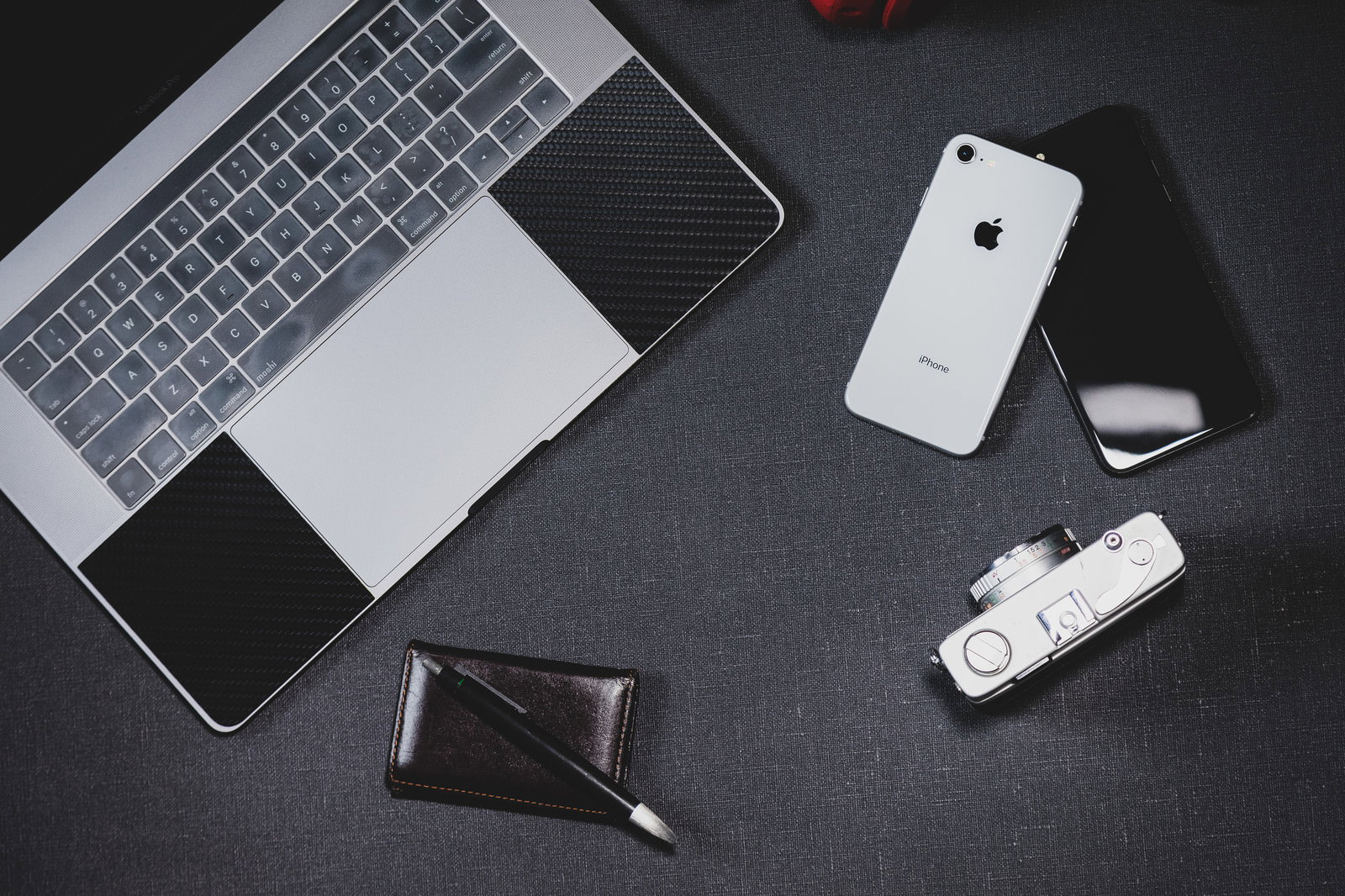 デスクの上に並んだiPhoneとMacBookとフィルムカメラ