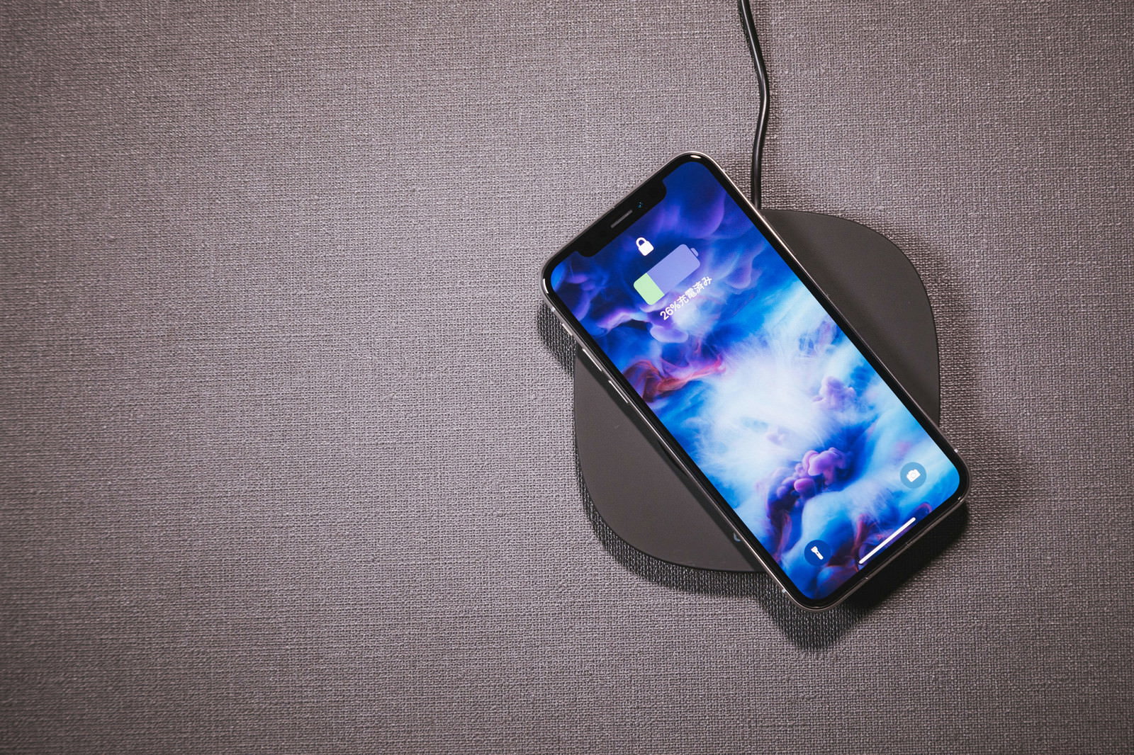iPhone Xをワイヤレス充電パッドに置く手元
