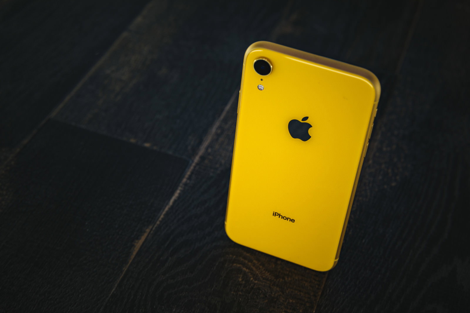 黒い大理石調の表面に置かれた黄色いiPhone XR