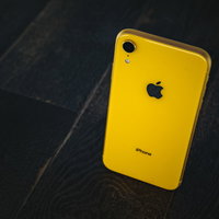 黒い大理石調の背景に置かれた黄色いiPhone XRの写真
