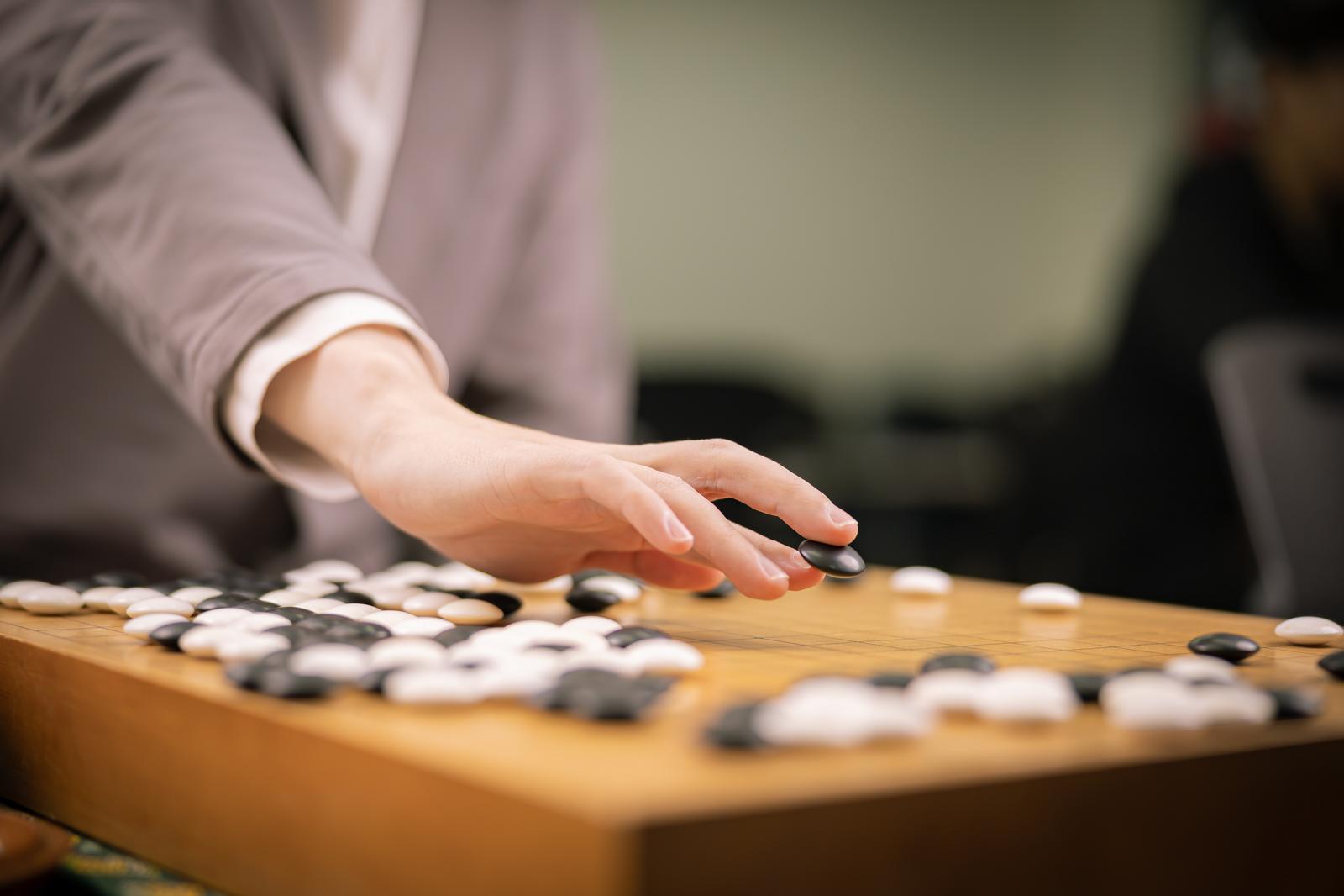囲碁盤に黒石を置こうとしている棋士の手元