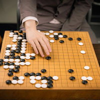 本因坊秀策が赤耳の一手を打つ瞬間、木製の碁盤での対局シーンの写真