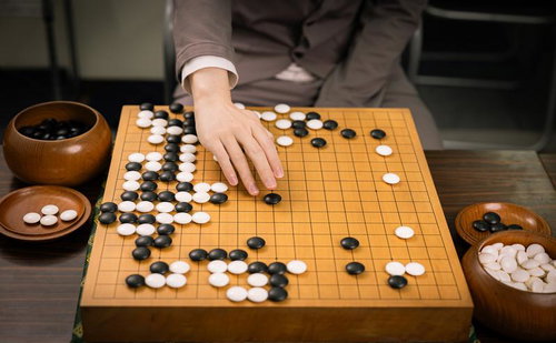 本因坊秀策が赤耳の一手を打つ瞬間、木製の碁盤での対局シーン