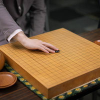 初手、天元。囲碁の対局開始、黒石を碁盤に置く瞬間の写真