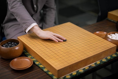 初手、天元。囲碁の対局開始、黒石を碁盤に置く瞬間