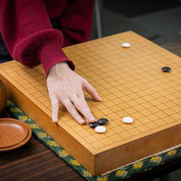 女性にも人気の囲碁。赤い袖をした女性が碁盤に黒石を置く対局風景の写真