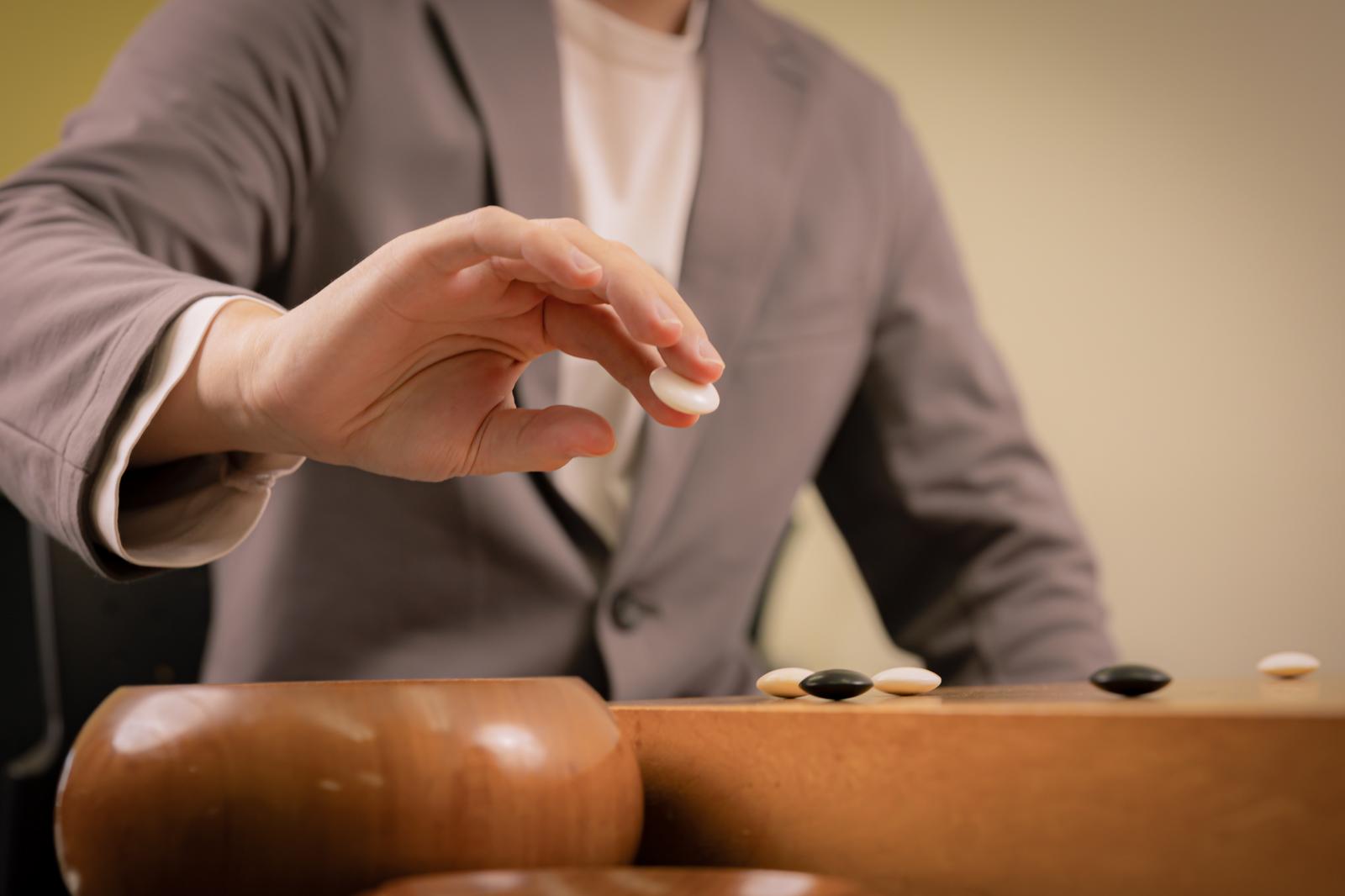 Close-up of hands about to place a Go stone on the Go board