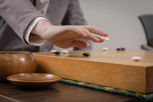 碁盤に置く直前、木製の碁盤上で碁石を爪の上でスライドさせる手元