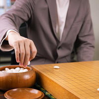 碁笥から白石をつかむ手元、囲碁の対局シーンの写真