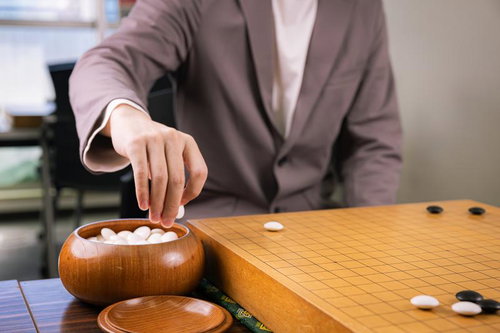 碁笥から白石をつかむ手元、囲碁の対局シーン