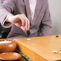 白番の対局者が碁笥から白石を取り出す瞬間の写真
