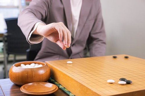 白番の対局者が碁笥から白石を取り出す瞬間