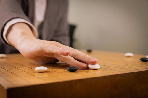 木製の碁盤に白石が着手される瞬間