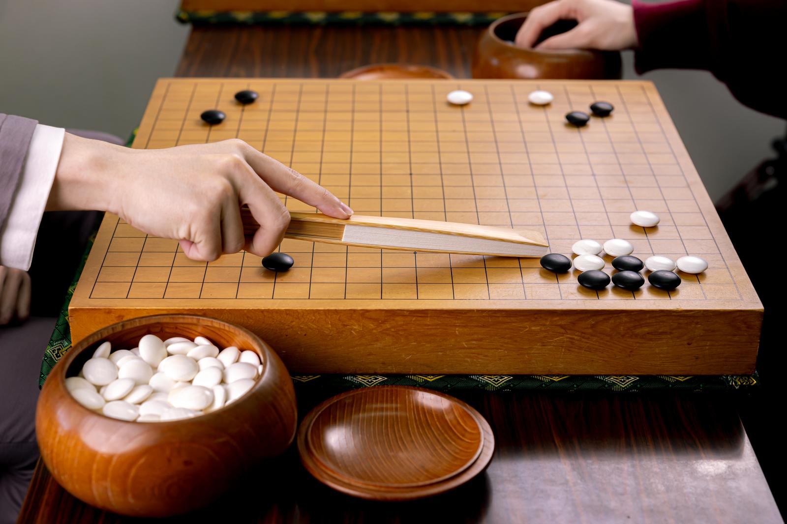 囲碁盤で扇子を使いながら盤面を解説する棋士の手元