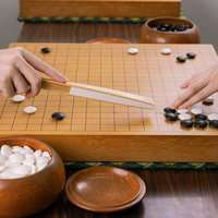 囲碁の指導碁で扇子を使い定石のポイントを示す場面の写真