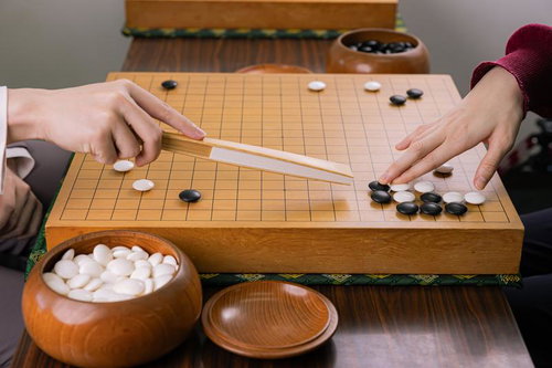 囲碁の指導碁で扇子を使い定石のポイントを示す場面