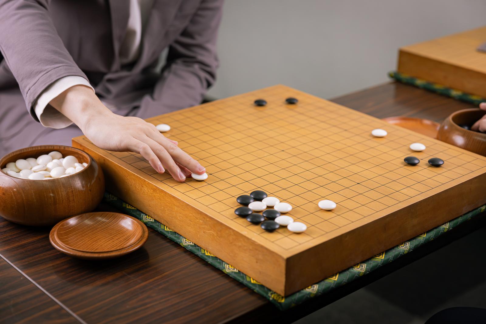 囲碁の碁盤上で白石を打つ人物の手元