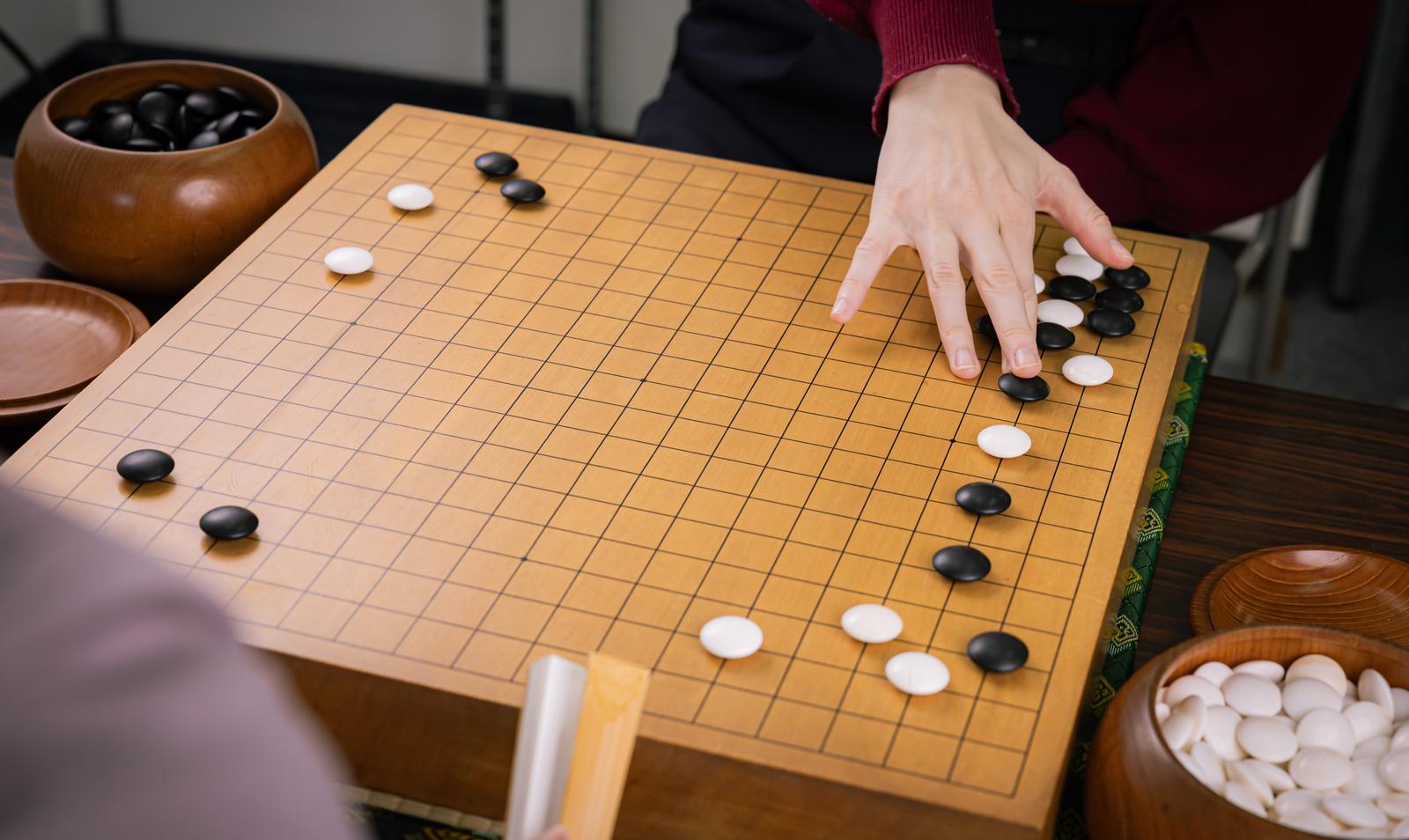 囲碁盤に黒石を置く棋士の手元のクローズアップ