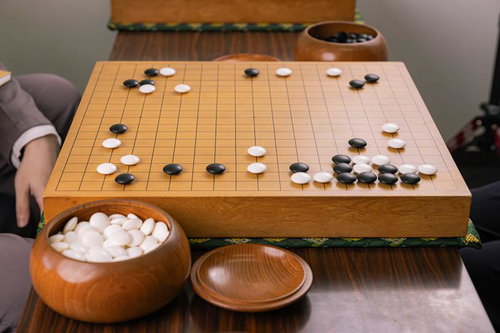 囲碁対局の進行中の盤面、木製の碁盤に配置された黒石と白石