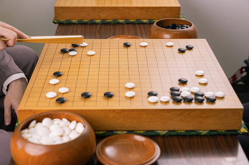 堅いシマリへのツケから始まる囲碁のサバキの手順を指導する様子