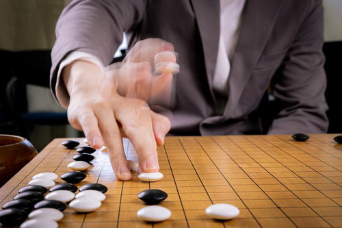 迷いなく放たれる光速の一手、碁盤に白石を打つ