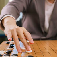 打ち下ろしの直後、碁盤に白石を置く棋士の手元の写真