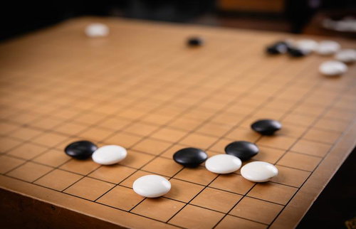 黒石の横ツケで仕掛ける攻めの場面を映す碁盤