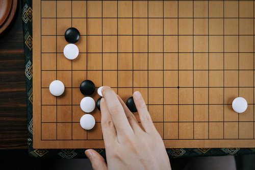 黒石の横ツケに対し白石を打つ囲碁の一手を指す場面