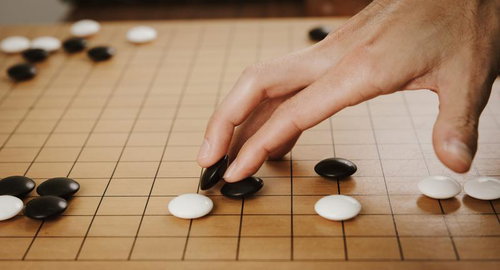 下の石を動かさぬよう抑え、碁石を滑らせて打つ繊細な一手