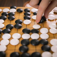 自滅手による盤面で黒石を置く対局者の瞬間の写真