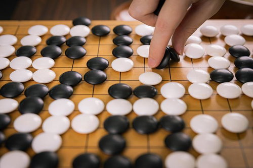 自滅手による盤面で黒石を置く対局者の瞬間