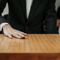 天元を狙う初手、碁石を木製盤面に滑らせて打つの写真