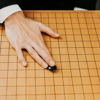 初手天元、堂々と放たれる第一着手を黒石で打つの写真