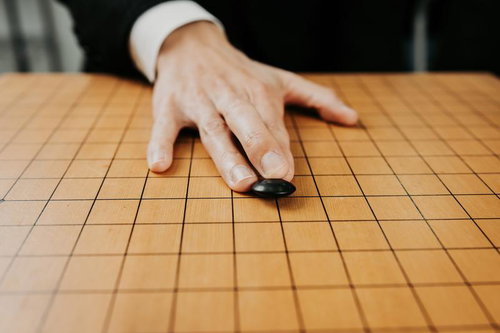 天元へ滑る黒石が一瞬浮く瞬間の碁盤での対局シーン