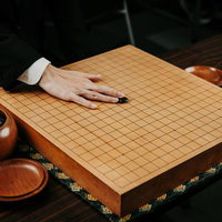 碁石を滑らせて天元に放つ、囲碁の初手を打つ瞬間の写真