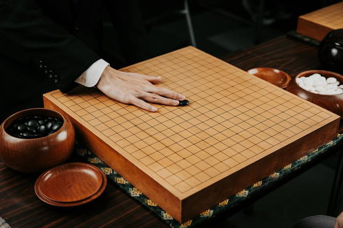 碁石を滑らせて天元に放つ、囲碁の初手を打つ瞬間