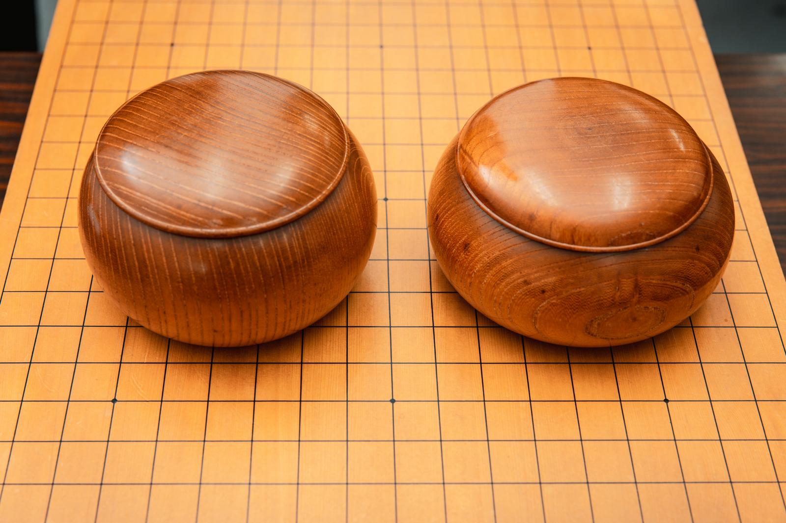 囲碁盤の上に並んだ2つの木製の碁笥