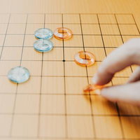 コンパクトな九路盤で囲碁の対局を楽しむ様子の写真